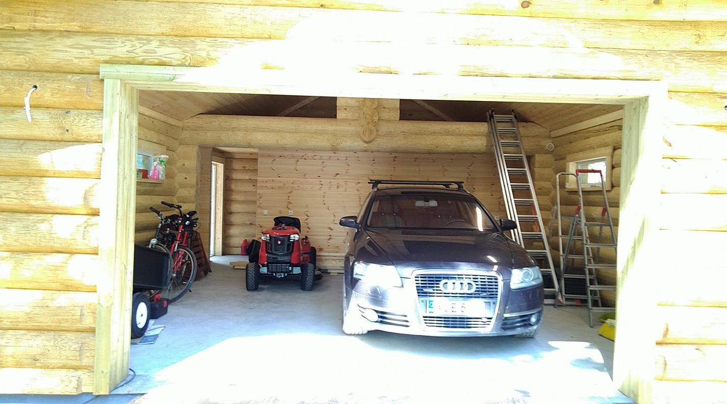 Hirrestä rakennettu autotalli. Avoimesta ovesta näkyy henkilöauto ja puutarhatraktori