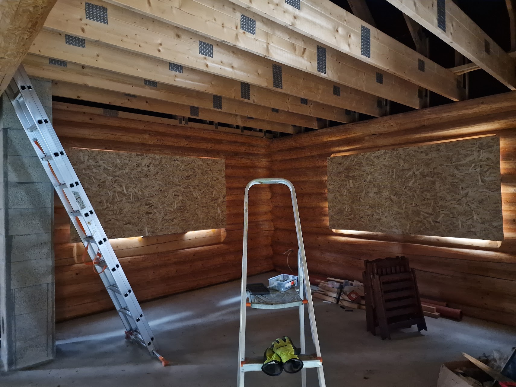 Keskeneräinen rakennus sisältä. Levyt ikkunoissa ja tikapuut kuvan etuosassa. Tikkailla työhansikkaat