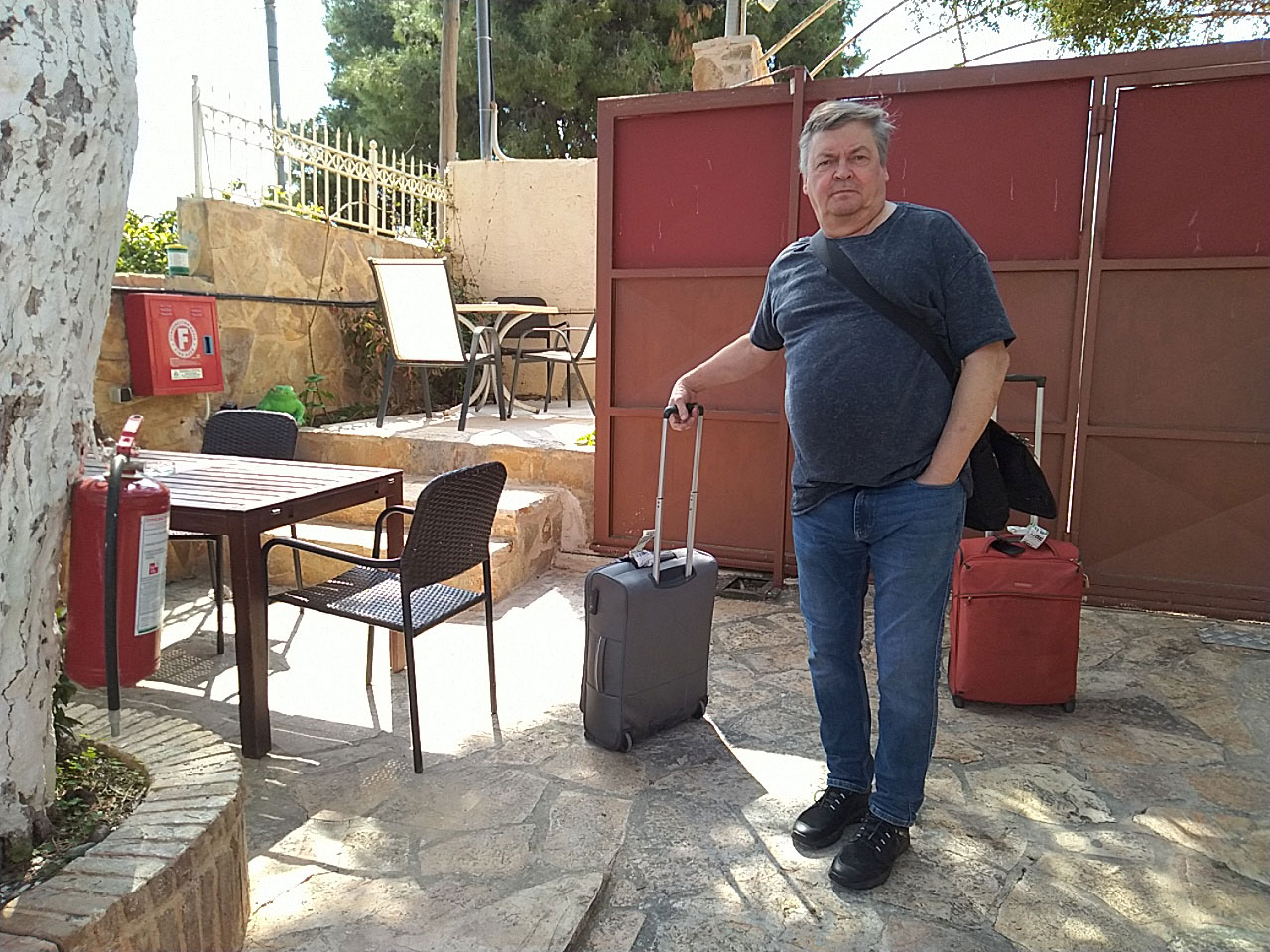 Mies ja matkalaukku kahvilan terassilla