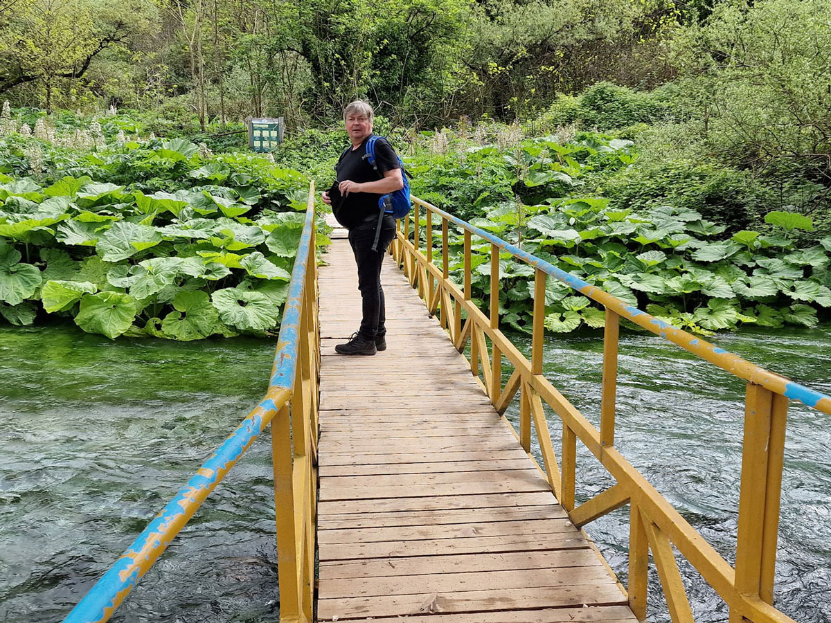 Mies seisoo joen yli vievällä kävelysillalla