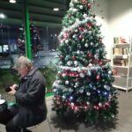 Mies istuu kahvilan pöydässä joulukuusen edessä