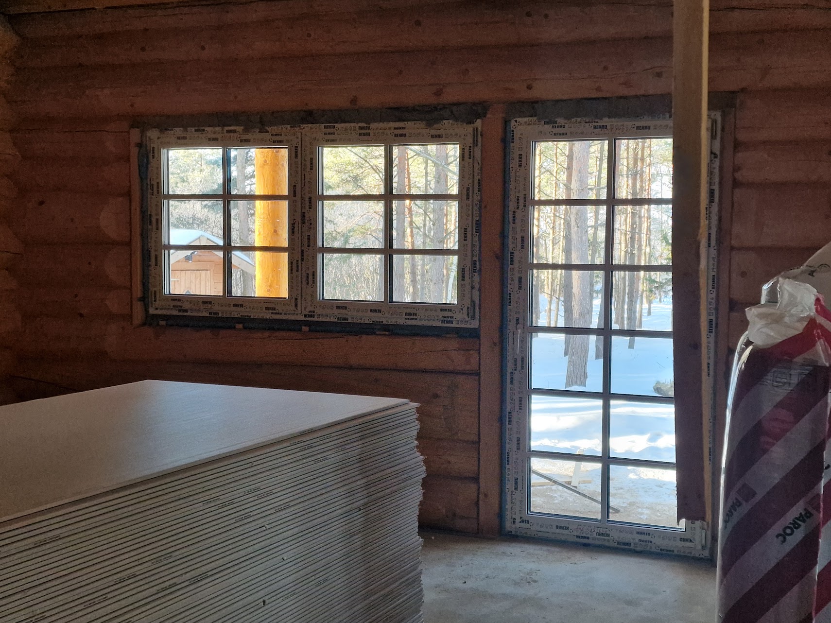 Hirsirakennus sisältä. Lasiovi ja ikkuna, joista näkyy metsä