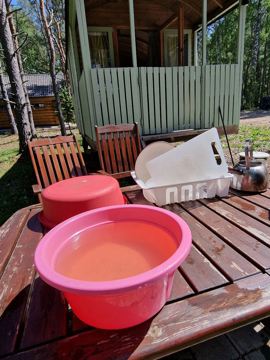 Vihreän lännentyylisen vankkurin edessä on ruskea pöytä, jolla vadillinen tiskivettä ja taustalla tiskatut astiat telineessä