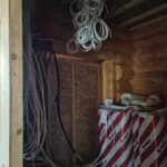 Hämärän huoneen katosta roikkuu valkoisia johtoja nipussa